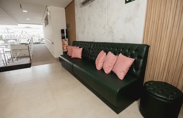 Sala de espera com sofá verde e almofadas rosadas
